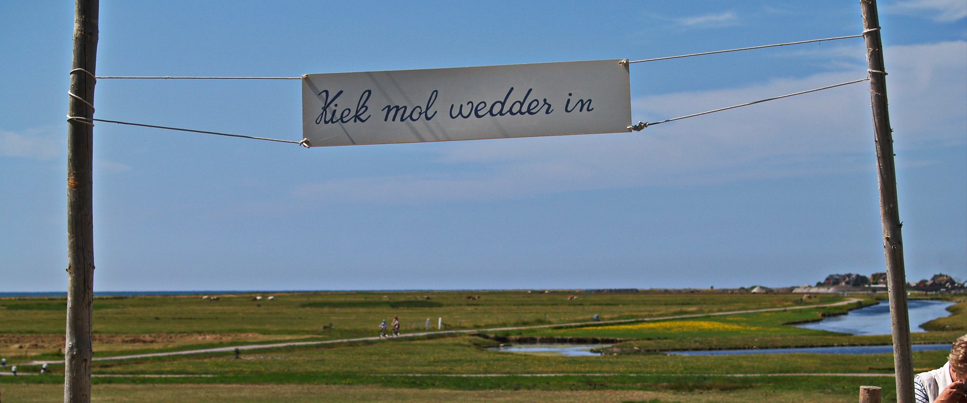 Transparent mit der Beschriftung "Kiek mol wedder in" auf Hooge mit Blick von Hanswarft in Richtung Westen