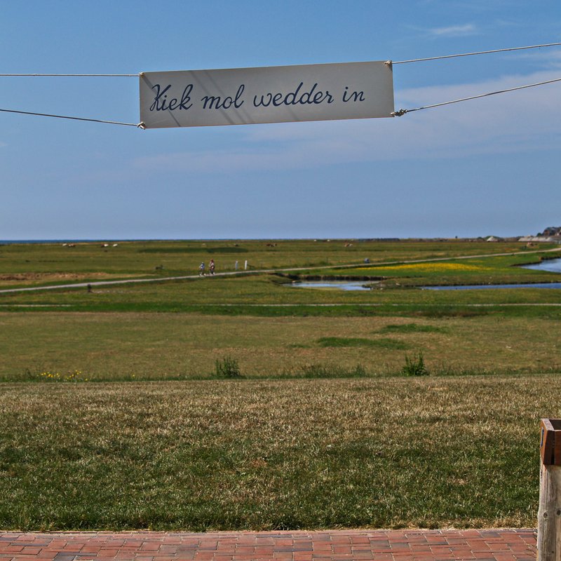 Transparent mit der Beschriftung "Kiek mol wedder in" auf Hooge mit Blick von Hanswarft in Richtung Westen